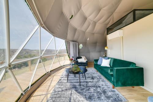 a living room with a green couch and large windows at Catskills Glamping at The Deer Dome in Franklin! in Franklin