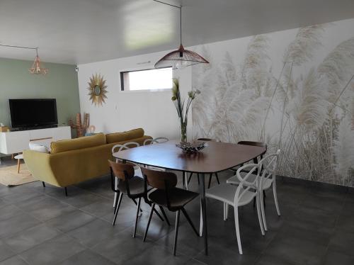 une salle à manger avec une table, des chaises et un canapé dans l'établissement maison au calme avec piscine proche de l'ocean, à Erdeven