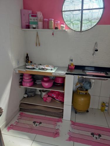 eine Küche mit rosa Wänden und Regalen mit rosa Geschirr in der Unterkunft aconchegante casa - lagoinha in Nova Iguaçu