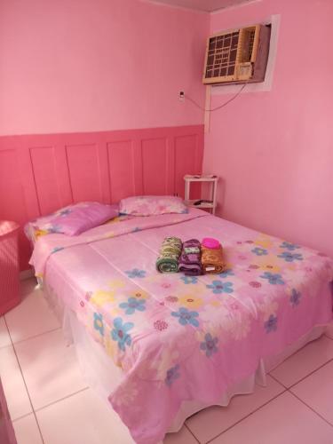 ein rosa Schlafzimmer mit einem Bett mit Schuhen darauf in der Unterkunft aconchegante casa - lagoinha in Nova Iguaçu