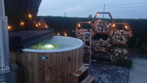 a hot tub with a pile of wood and lights at Vakantiehuis De Horizon in Reningelst