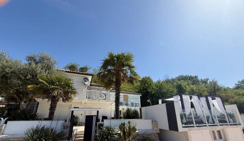 a white house with palm trees in front of it at Villa Nar in Ljubuški