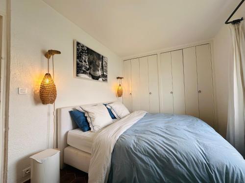 une chambre avec un lit avec des oreillers bleus et blancs dans l'établissement La Plage Grand Appt vue mer, à Grimaud