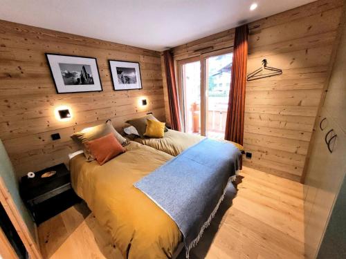 une chambre avec un lit dans une pièce aux murs en bois dans l'établissement Résidence Flocon Bleu - Appartement de Charme, confort, proximité centre MAE-4591, aux Gets