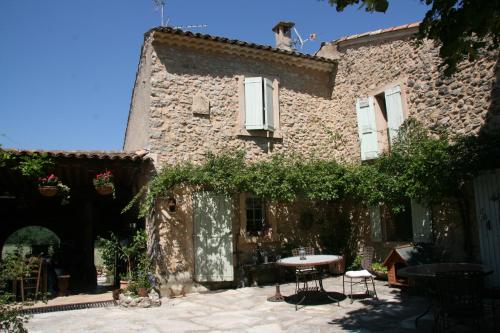 a stone house with a table in the courtyard at Le Jas des Nevières in Pierrerue