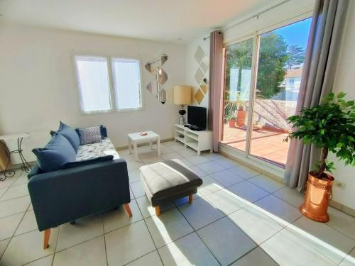 - un salon avec un canapé bleu et une porte coulissante en verre dans l'établissement Le 109 : Calme, terrasse, garage et confort en pleine ville, à Montpellier