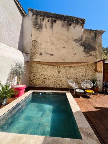 - une piscine au milieu d'une terrasse avec 2 chaises dans l'établissement Maison de ville avec piscine, à Châteaurenard
