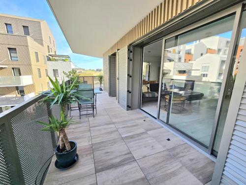 d'un balcon avec des portes en verre et des plantes en pot. dans l'établissement PAVLOVA : Calme, vue, élégant, spacieux, sûr et central, à Montpellier