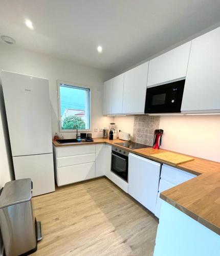 Elle comprend une petite cuisine avec des placards blancs et une fenêtre. dans l'établissement Villa moderne avec Piscine chauffée et 5 chambres, à Marseillan