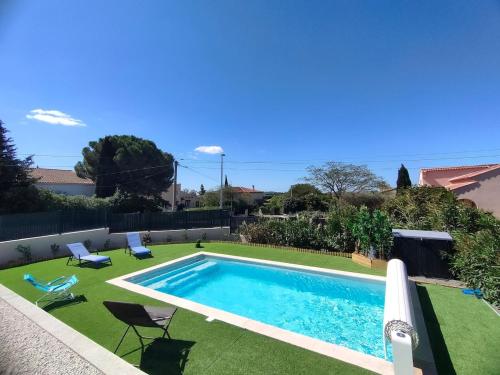 - une piscine dans une cour avec de l'herbe verte dans l'établissement Villa moderne avec Piscine chauffée et 5 chambres, à Marseillan