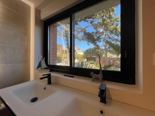 une salle de bain avec un lavabo et une grande fenêtre dans l'établissement Les Tamaris - Grande Maison de Plage - Jacuzzi, à Carolles