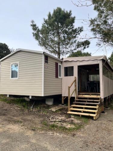 une petite maison avec une terrasse couverte et des escaliers. dans l'établissement Mobil Home, à Mimizan-Plage