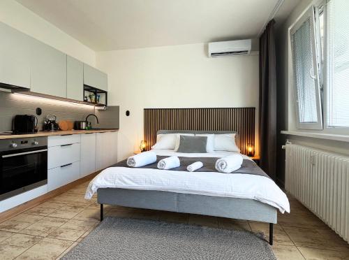 a bedroom with a large bed and a kitchen at New cozy studio, AC & Balcony in Bratislava
