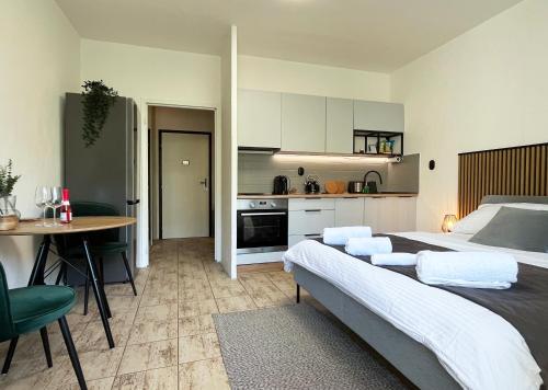 a bedroom with a bed and a table and a kitchen at New cozy studio, AC & Balcony in Bratislava