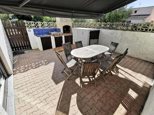 un patio avec une table et des chaises sous un parasol dans l'établissement Résidence Les Patios 1 - VILLA 3 PIECES 6 couchages PORT LEUCATE MAE-5584, à Port-Leucate