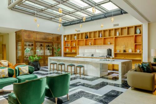 a kitchen with a large counter and green chairs at Recoleta Grand, Buenos Aires, a Tribute Portfolio Hotel in Buenos Aires