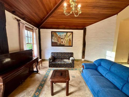 a living room with a blue couch and a piano at Casa Rústica - 3 vagas de garagem - Pet Friendly com vista para Serra de São José in Tiradentes