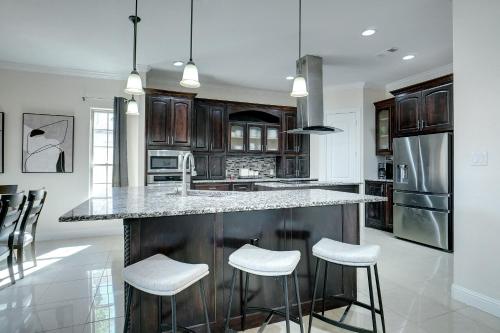 a kitchen with a large island with stools at GORGEOUS 5-bd 4ba w Pool, Hot Tub, 2 kitchens, & Game Room Near Dallas Airports! in Irving