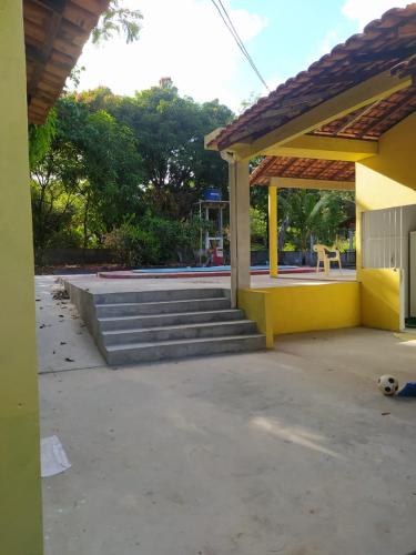 a yellow house with stairs and a dog laying on the ground at La Fortaleza Marapanim in Marapanim