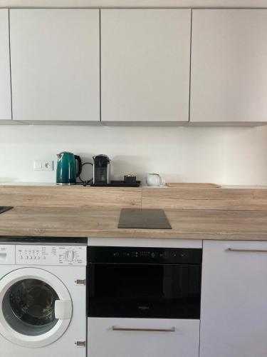 une cuisine avec des armoires blanches et une machine à laver dans l'établissement Charmante petite maison à Saillé, village classé proche plages, à Guérande