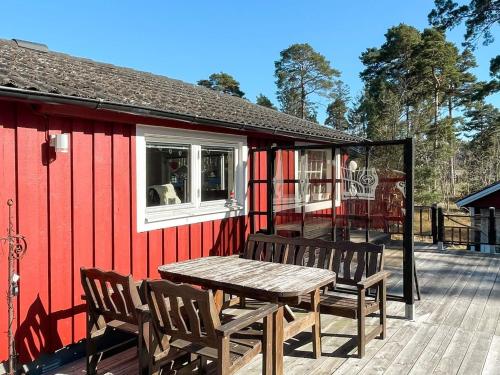 a picnic table and chairs on the deck of a red house at 7 person holiday home in Mönsterås in Mönsterås