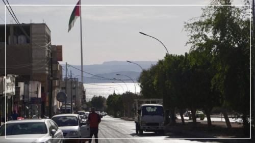 a man walking down a busy city street with cars at النخيل للشقق الفندقية ALnakheel hotel apartment in Aqaba
