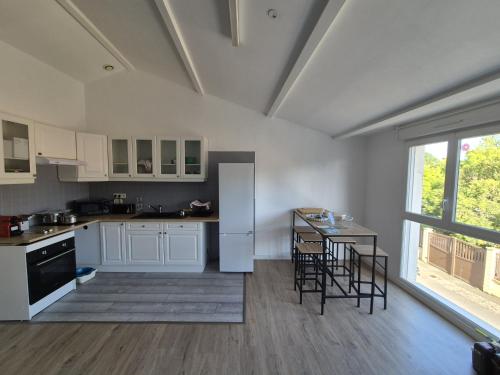 une cuisine avec des armoires blanches et une table avec des chaises dans l'établissement 202 - Gite de Marius, à Oudon