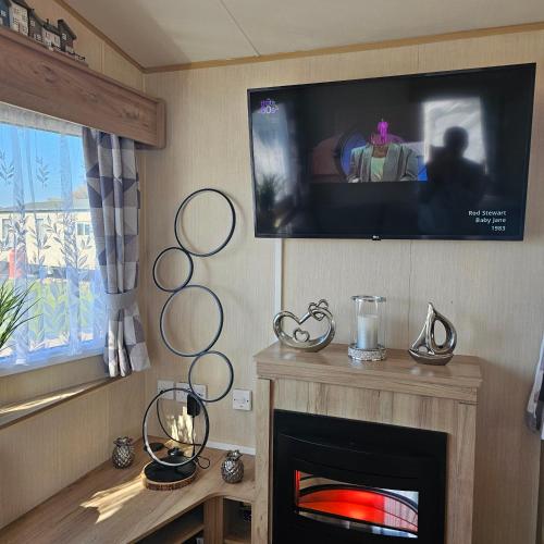 a living room with a tv and a fireplace at Magic Caravan Camber Sands in Camber
