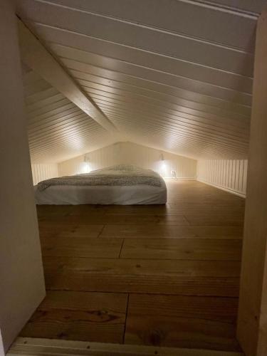 a bed in a small room with a wooden floor at Nybyggd stuga nära centrum och tågstation in Falkenberg