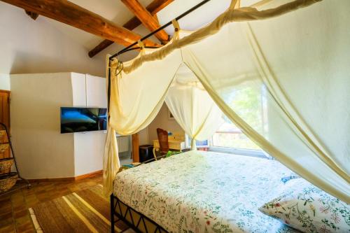 une chambre avec un lit à baldaquin et une fenêtre dans l'établissement Le Mas des lys - Guest houses au coeur de la Provence dans un parc paysagé avec piscine, sauna et boulodrome, à Grans