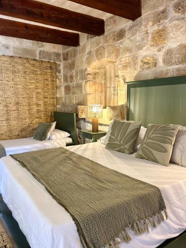 two beds in a room with stone walls at Ta Skorba Farmhouse Mgarr in Mġarr