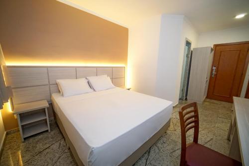 a bedroom with a white bed and a chair at Hotel Golden Park Sorocaba & Convenções by Nacional Inn in Sorocaba