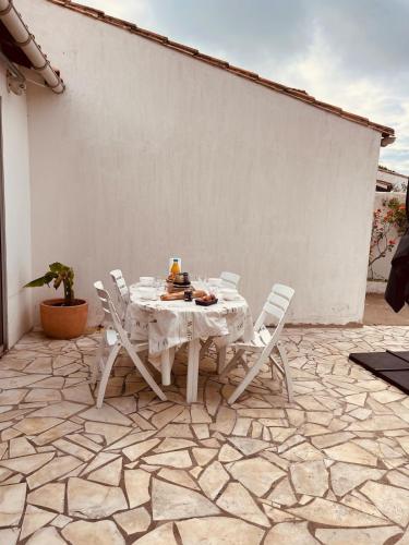 une table et des chaises blanches sur une terrasse en pierre dans l'établissement La maison des courlis, à Rivedoux-Plage