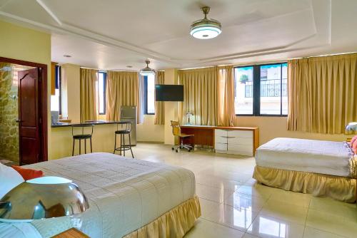 a hotel room with two beds and a desk at Hotel Libertad at historic main street in Santo Domingo