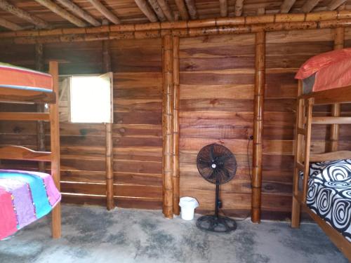 a room with a fan in a log cabin at Oso Hostel Cabaña Los Linderos in Santa Marta