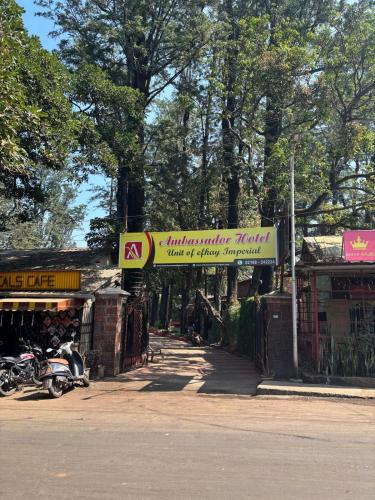 a sign for an amusement park with a motorcycle parked on a street at H O T E L Ammbasador in Panchgani