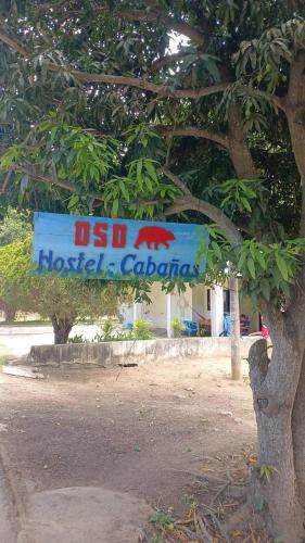 a sign in front of a tree with a sign at Oso Hostel Cabaña Los Linderos in Santa Marta