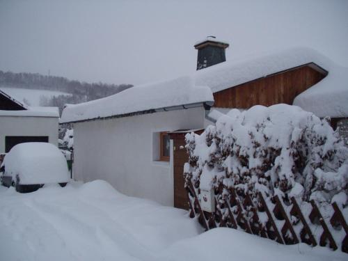 a house covered in snow next to a fence at Bungalov Mladé Buky in Mladé Buky