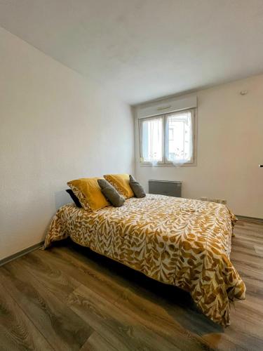 ein Schlafzimmer mit einem großen Bett mit gelben Kissen in der Unterkunft Studio calme proche de la gare in Amiens