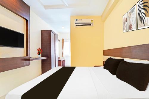 a bedroom with a bed and a tv on the wall at Super Collection O Gandhipuram in Coimbatore
