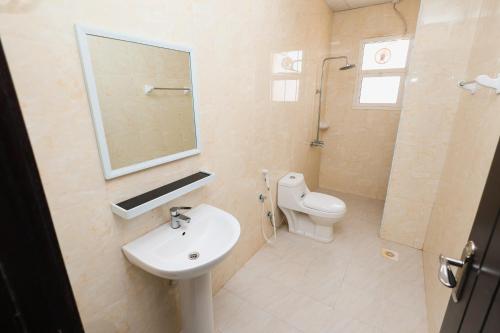 a bathroom with a sink and a toilet and a mirror at الحي التجاري نسائم صلاله للشقق الفاخرة Nassayem Salalah Downtown in Salalah