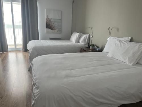 リムースキにあるHôtel Normandieの白いシーツが敷かれたホテルの部屋にベッドが2つある