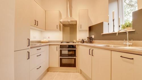 a kitchen with white cabinets and a sink at The Gate House-Wyndale Living- West Malvern in Great Malvern
