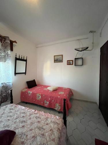 a bedroom with two beds and a red blanket at Quarto da casa da avó in Cercal