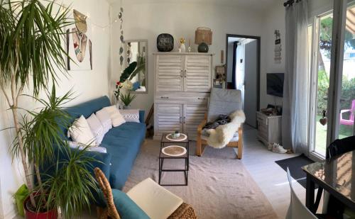 un salon avec un canapé bleu et des plantes dans l'établissement Plain pied - Appartement dans résidence sous les pins, au Cap d'Agde