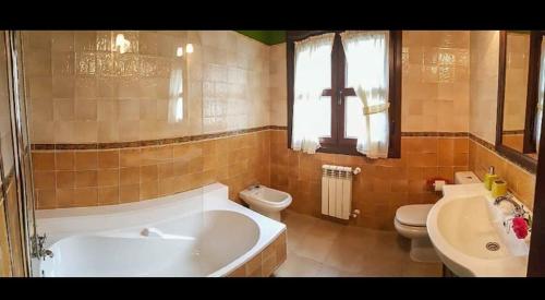 a bathroom with a tub and a toilet and a sink at Apartamentos Picos de EUROPA in Dego