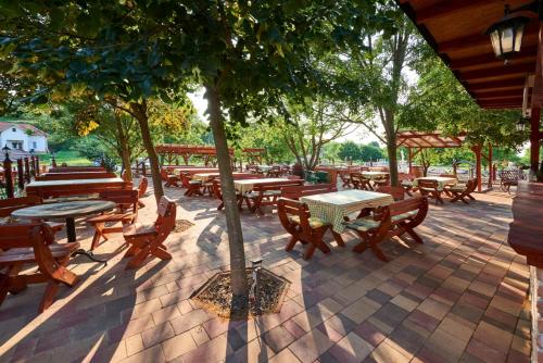 a patio with wooden tables and benches and trees at Szent Kristóf Borbirtok in Zamárdi