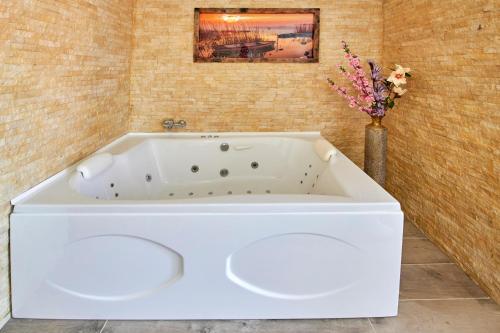 a white bath tub in a bathroom with a vase of flowers at Szent Kristóf Borbirtok in Zamárdi