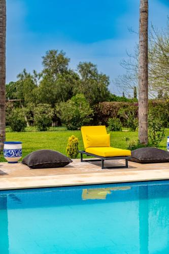 a yellow chair sitting next to a swimming pool at Domaine Terra Cotta - Villa de luxe avec piscine sans vis-à-vis in Souk el Had