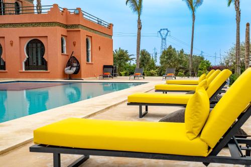 a row of yellow lounge chairs next to a swimming pool at Domaine Terra Cotta - Villa de luxe avec piscine sans vis-à-vis in Souk el Had